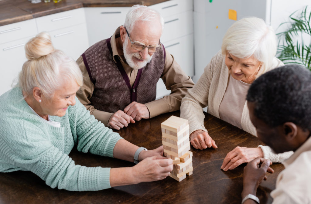 Seniors engaging with one another playing Jenga while sitting in living room of senior community