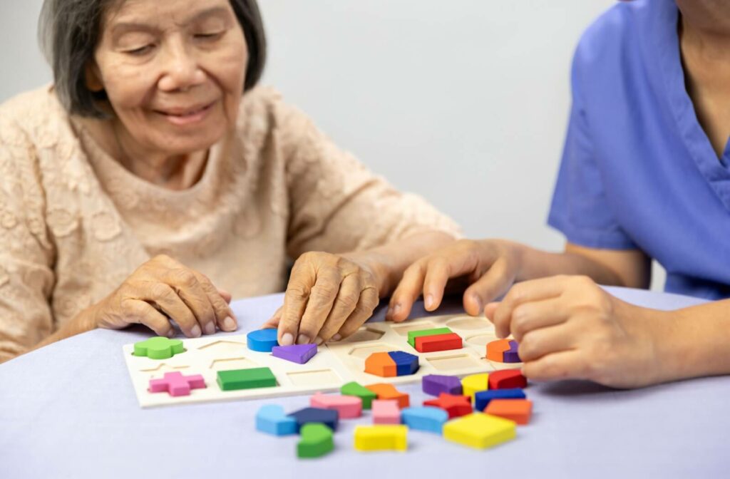 A nurse assists a senior with dementia in memory care with a puzzle game meant to help support cognitive function